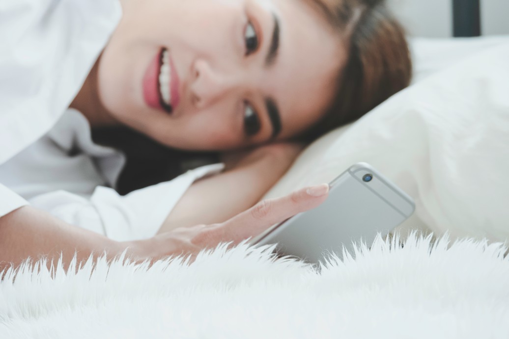 Young woman use smartphone on bed